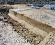 838920 Afbeelding van een bodemprofiel met achterin een laag met asresten op het terrein van een archeologische ...